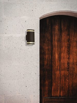 double outdoor wall light in black placed beside a wood door on a white outdoor wall